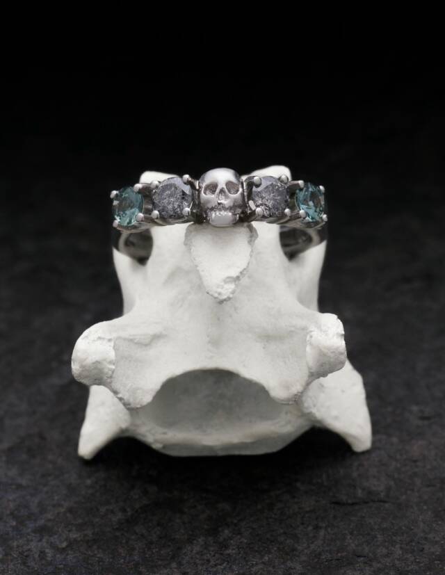 Platinum skull ring with diamonds for women presented on a bone.