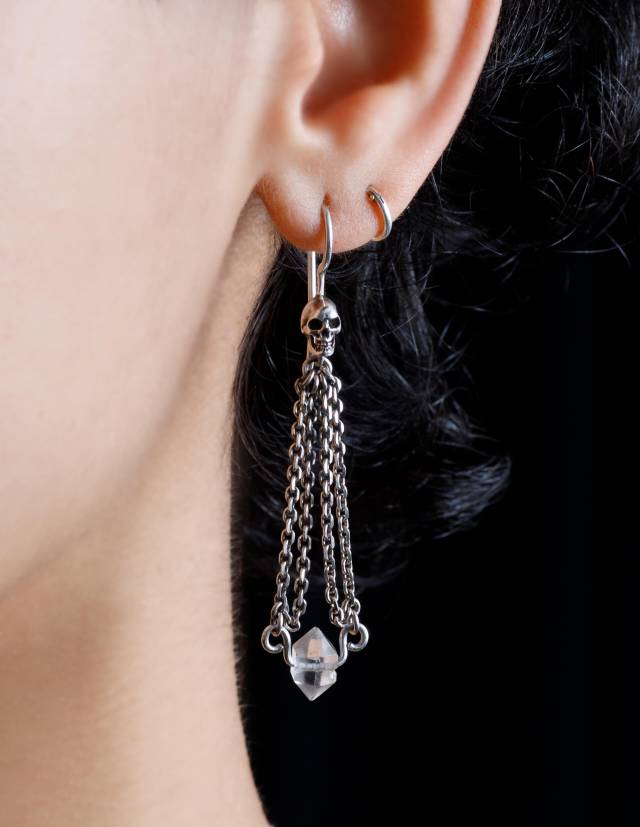 Close up of a person wearring a dainty skull chandelier earring with a clear herkimer crystal gemstone.