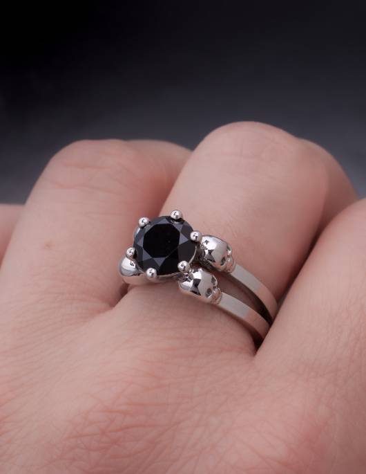 A gothic engagement ring made of silver with a round black gemstone worn, close up.