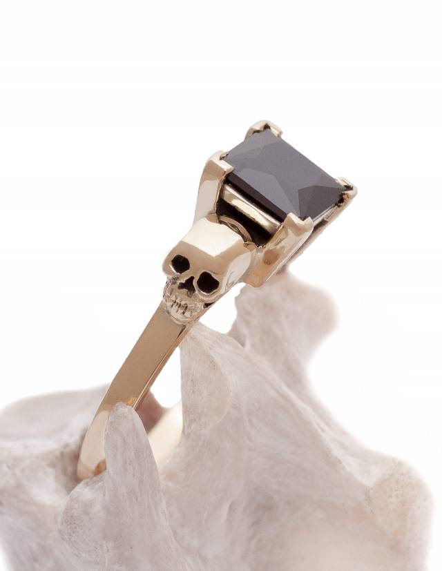 Detailed skull engagement ring made of solid yellow gold with black diamond.